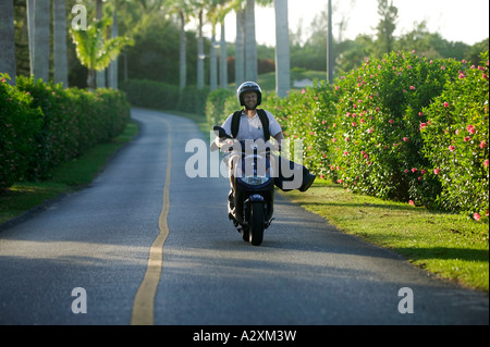Man Riding avec Clubs de Golf sur scooter dans les Bermudes, Banque D'Images