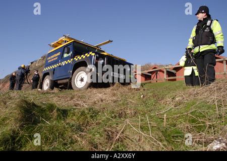 Les agents de la police et des garde-côtes qui travaillent ensemble en équipe à Branscombe beach Devon Janvier 2007 Banque D'Images