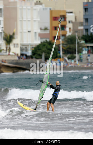 Windsurfer mâle en train rides board à travers les vagues en face des appartements et hôtels au large de la plage de El Medano Tenerife Banque D'Images