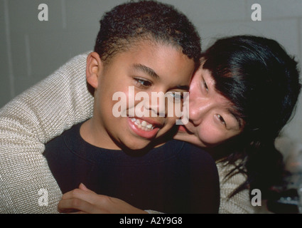 Leader Américain asiatique hugging boy age 27 et 8 dans le groupe de jeunes de la communauté. St Paul Minnesota USA Banque D'Images