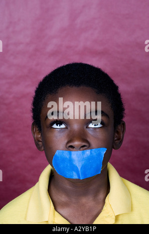 Jeune garçon avec du ruban adhésif sur sa bouche Banque D'Images