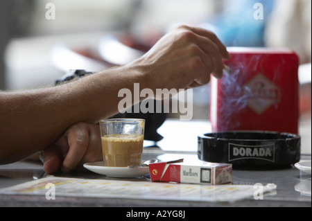 Tasse de café avec des cigarettes et barraquito mans part mettre en cigarette cendrier fermer jusqu'au café de la rue Banque D'Images