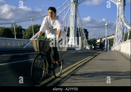 Woman riding bicycle avec légumes en face panier sur albert bridge crossing River Thames 1996 Banque D'Images