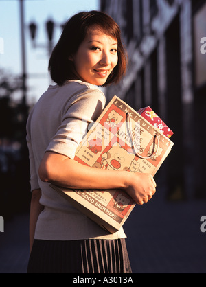 A chinese young woman holding a Shopping bag and smiling Banque D'Images