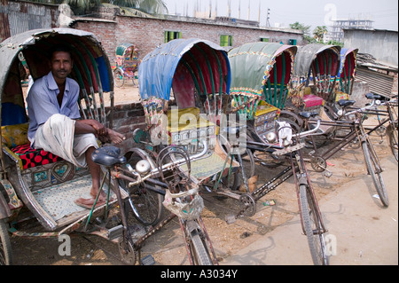 Un rickshaw puller assis sur le siège passager d'un rickshaw stationné à Dhaka Bangladesh Banque D'Images