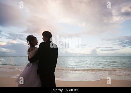 Les nouveaux mariés sur la plage au coucher du soleil Banque D'Images