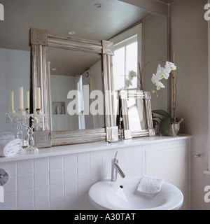 Salle de bains contemporaine blanche avec petits miroirs encadrés appuyé contre un mur à mur miroir Banque D'Images