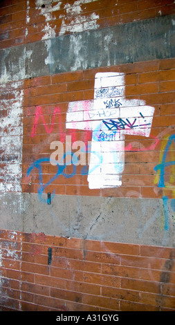 Croix blanche de l'écriture graffiti peint sur un mur de brique rouge Banque D'Images