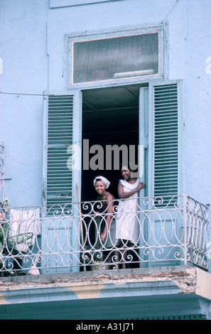 Deux femmes, l'un souriant un nettoyant et un foulard et du godet, à partir d'un balcon d'une chambre bleu pâle à La Havane, Cuba Banque D'Images