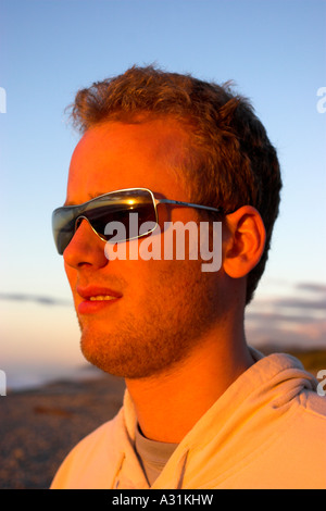 Jeune homme regardant le soleil sur l'horizon lointain. Banque D'Images