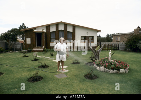 Microcosme de l'apartheid de l'Afrique du sud de kleinmond un homme blanc avec un tuyau d'arrosage jardin par une maison 1988 Banque D'Images