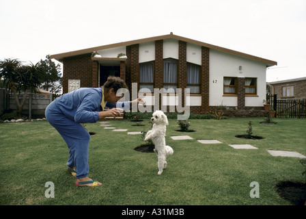 Microcosme de l'apartheid de l'Afrique du sud de kleinmond un blanc femme jouant avec un caniche dans un jardin par une maison 1988 Banque D'Images