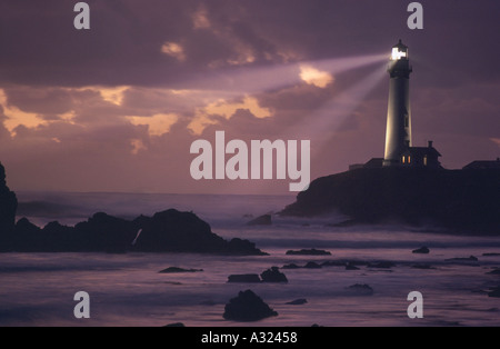 Les faisceaux lumineux rayonnent de Pigeon Point Lighthouse au-dessus des côtes rocheuses à la tombée de la Californie Banque D'Images