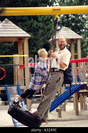 Man and boy standing on rope swing dans un parc sur l'Île Granville Vancouver Canada Banque D'Images