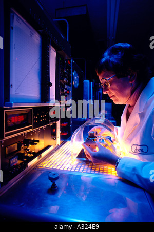 Une femme Technicien de laboratoire se concentre sur son travail tandis que l'intérieur d'une salle blanche de fabrication électronique Banque D'Images