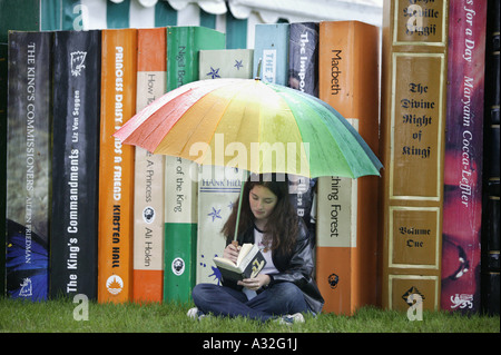 Un visiteur de l'Hay-on-Wye Book Festival à Powys, Pays de Galles, la lecture devant un bouquet de livres grand format sous la pluie Banque D'Images