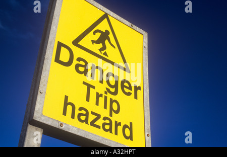 Signe jaune et noir contre ciel bleu profond à l'image emblématique de la figure de trébucher et de mots Danger trébuchement Banque D'Images