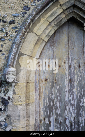 Détail de l'anglais précoce avec une voûte en pierre sculpté usés de corbel et patiné tête de femme médiévale porte et mur de silex Banque D'Images