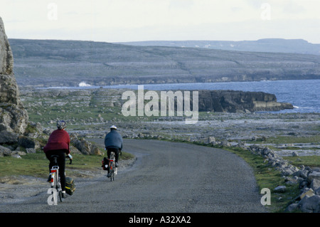 Couple à vélo sur route côtière dans le Burren, comté de Clare, Irlande Eire 1995 Banque D'Images