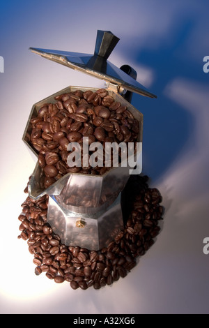 Cuisinière cafetière italienne entouré de et plein de grains de café Banque D'Images