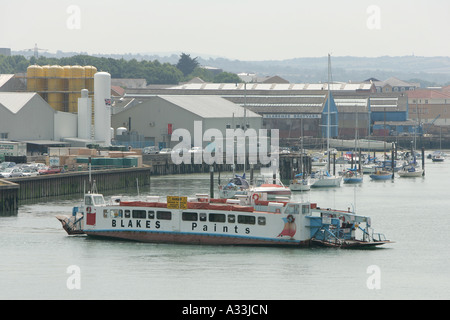 Ferry de la chaîne prend de passagers sur le port de Cowes sur l'île de Wight comme un yacht passe l'entrée du port Banque D'Images