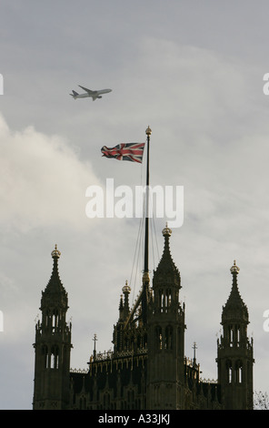 Un avion vole sur les chambres du parlement dans les bâtiments de la tour Victoria London England Banque D'Images