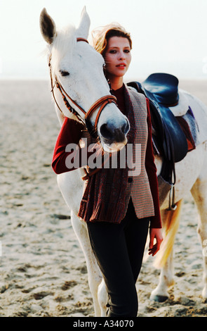 Une jeune femme, à l'aise ici avec des hors-blanc séjournez au coucher du soleil sur une plage solitaire . Banque D'Images