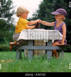 Deux enfants assis à une table de pique-nique partage d'une grappe de raisin Banque D'Images