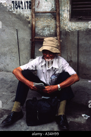 Homme assis sur la rue Hanoi Vietnam lecture Banque D'Images