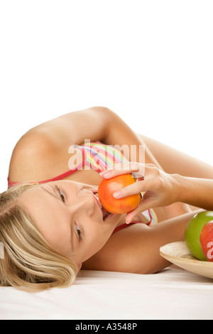 Young woman eating persimmon Banque D'Images