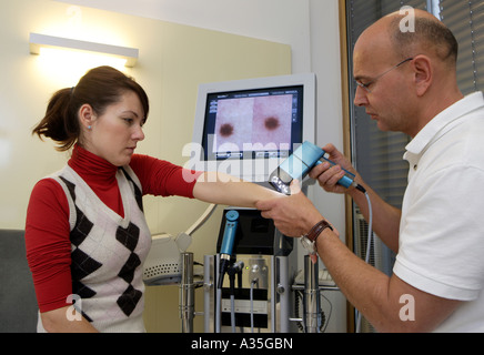 Le spécialiste de la peau MD Serko von Düben examine un patient avec un dermatoscope vidéo Banque D'Images