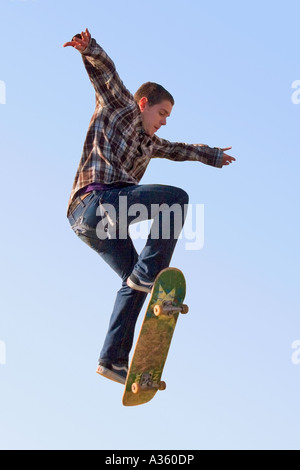 Une jeune adolescente de la hanche vole haut dans le ciel sur sa planche à roulettes. Banque D'Images