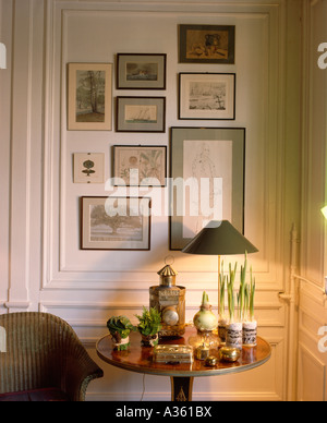 Collection de photos sur le mur derrière la petite table ancienne avec la lampe allumée et l'ensemble de petites boîtes circulaires Banque D'Images