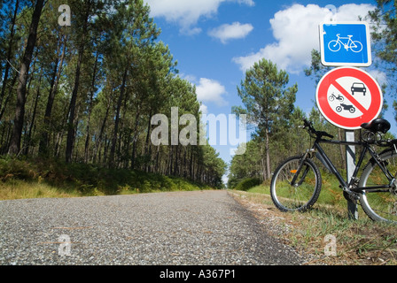 Location garé contre un panneau routier sur une piste cyclable traversant la forêt des Landes, France. Banque D'Images