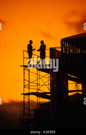 Silhouette de deux travailleurs de la construction debout sur des tours d'échafaudage de construction Banque D'Images