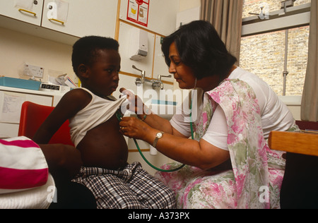 Une femme médecin asiatique examine un enfant dans sa chirurgie à London UK Banque D'Images
