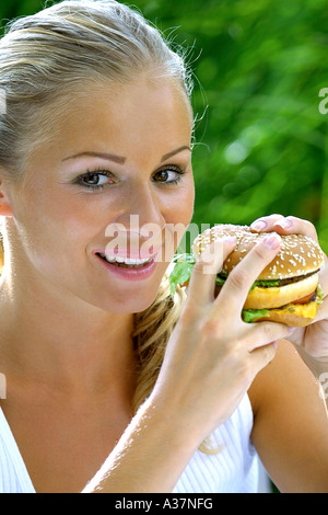 Junge Frau isst einen Hamburger, woman eating hamburger Banque D'Images