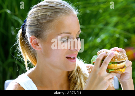 Junge Frau isst einen Hamburger, woman eating hamburger Banque D'Images