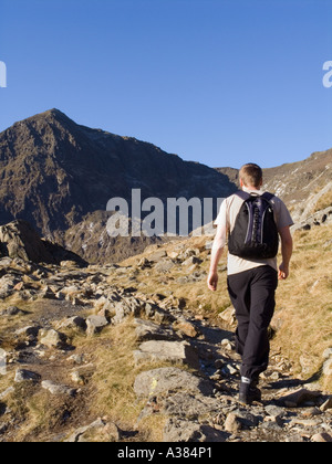 Jeune homme marche en montée seule sur la piste PYG avec Mont Snowdon (Yr Wyddfa) peak dans le parc national de Snowdonia Gwynedd North Wales UK Banque D'Images