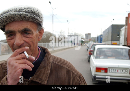 Un vieil homme qui fume une cigarette sur le pont en attendant de traverser la frontière de l'Europe à la Russie dans la région de Narva Banque D'Images