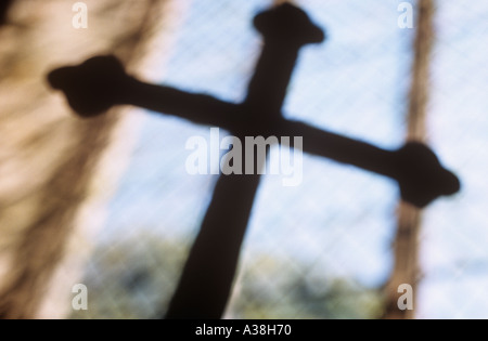 Crucifix de flou artistique silhouetté contre grand diamant brut fenêtre au plomb Banque D'Images