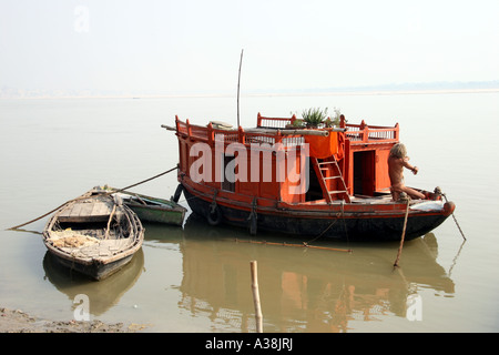 Sadhu lave-sur son bateau amarré sur la rive du Gange, Varanasi, Uttar Pradesh, Inde Banque D'Images