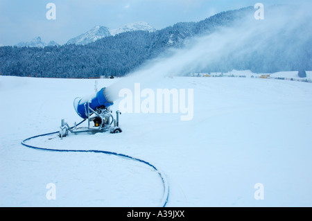 Un canon à neige en action sur une piste de ski au petit matin Banque D'Images