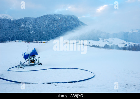 Un canon à neige en action sur une piste alpine Banque D'Images