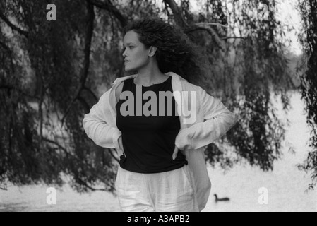Belle femme portrait féminin posent park à regarder regarder penser lake tree willow mains bw longs cheveux d'âge moyen Banque D'Images