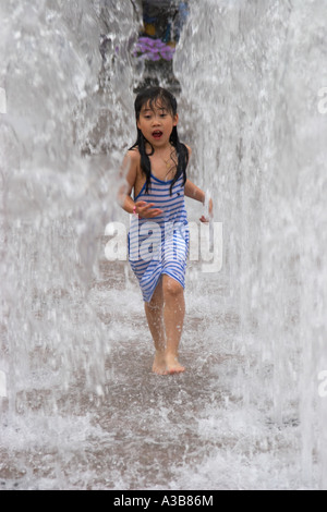 Jeune fille courir à travers Fontaine Banque D'Images