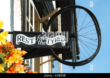 Gros plan de roue de vélo pour le jeu fatigué sur les mots pun sur le lit et petit déjeuner établissement signe inhabituel dans le ciel bleu jour à Hay on Wye Powys Wales UK Banque D'Images