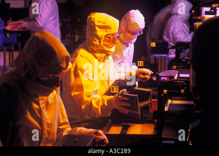 Groupe des travailleurs de l'inspection d'IDT Technicien de laboratoire une gaufrette dans une chambre propre dans de très faibles lumières Banque D'Images
