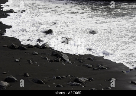 Plage de sable volcanique noir à marée montante s'écoule sur le sable à los Gigantos dans Tenerife Espagne Banque D'Images