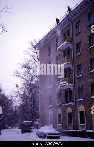 Nettoyer les travailleurs à Moscou avec toit toit de claquer la neige voiture garée à proximité du projet de logement. Nettoyage des toits d'hiver est important service à Moscou. Banque D'Images